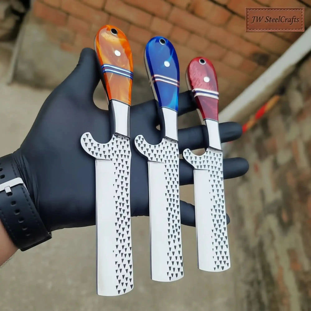 Held between gloved fingers, three straight razors with orange, blue, and red swirl resin handles and dimple-patterned blades
