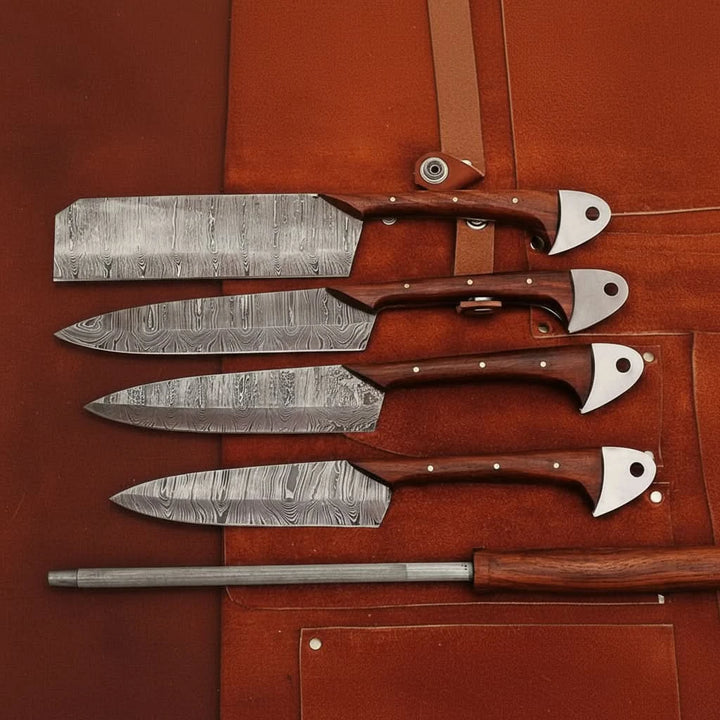 Handcrafted Damascus steel kitchen knife set with honing rod displayed on brown leather knife roll against white background.
