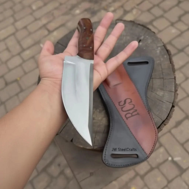 Stitched black and brown leather sheath paired with a custom knife featuring RCS branding on the blade.