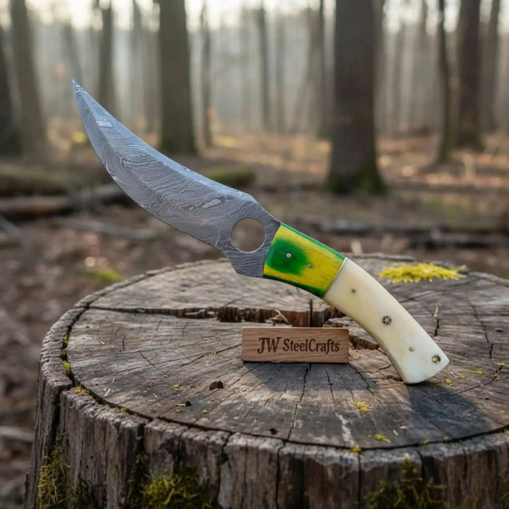 Custom fixed blade knife with round blade hole, curved Damascus steel blade, cream handle, and green yellow inlay.