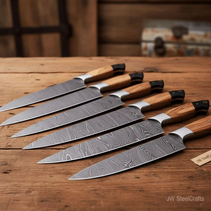 Collection of Damascus steel kitchen knives arranged on a wooden tabletop