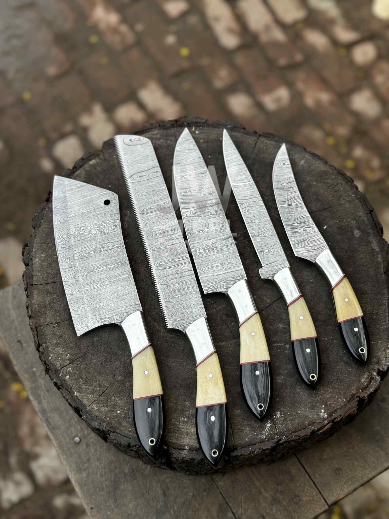 Set of five knives with black and beige handles on a wooden block.