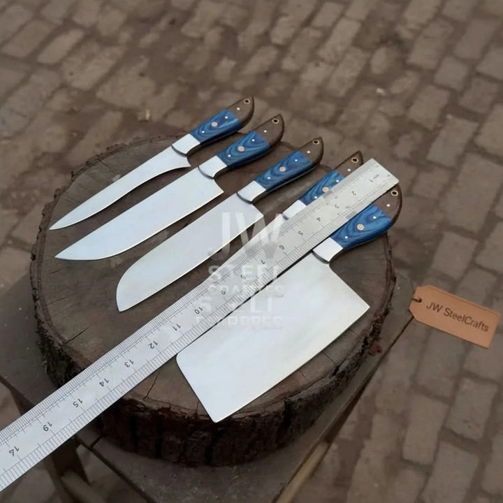 Size measurement of a custom Damascus steel kitchen knife set featuring blue wood and brass pin handles, displayed on a wooden log.