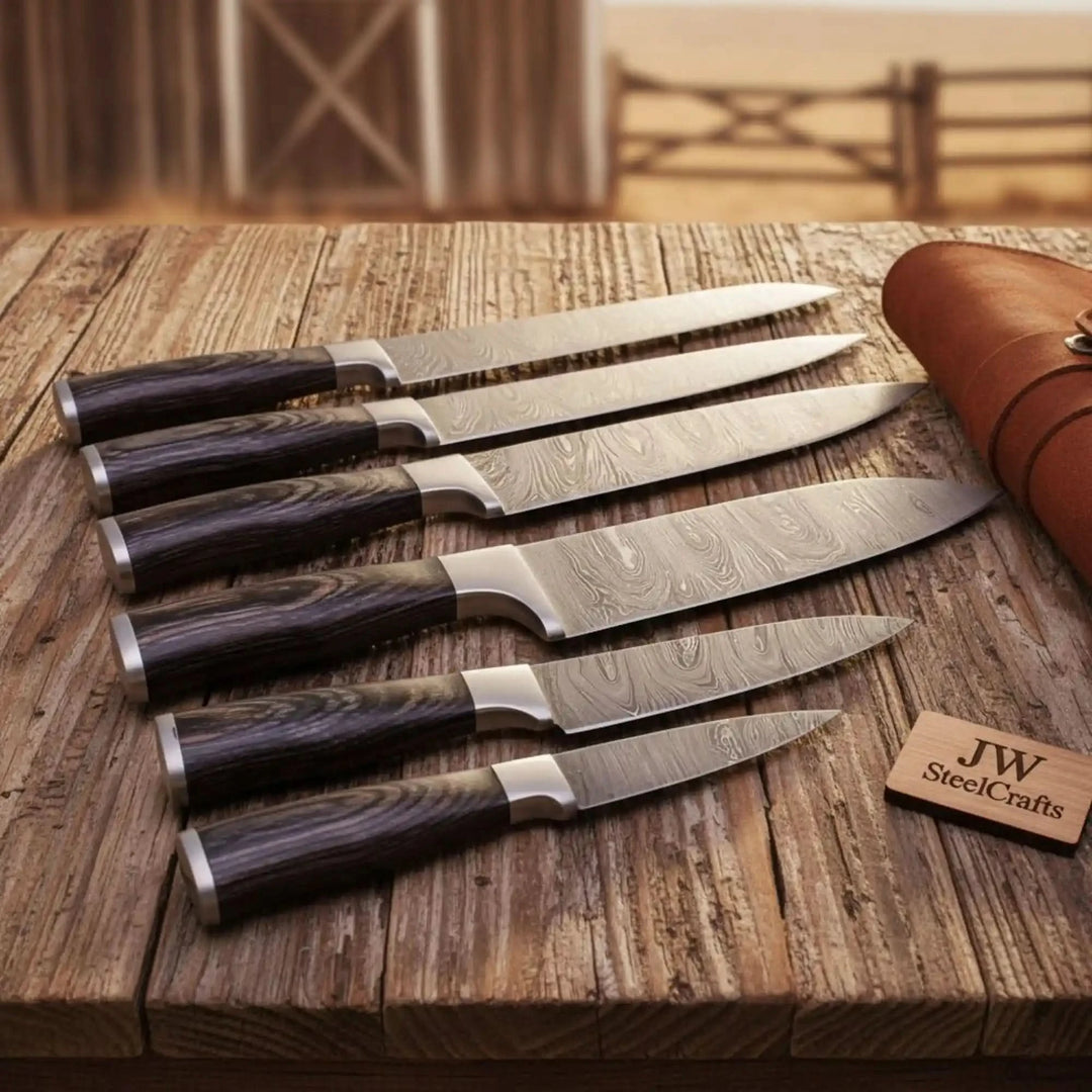 Dark wood chef knife set with Damascus steel blades displayed on rustic wood.

