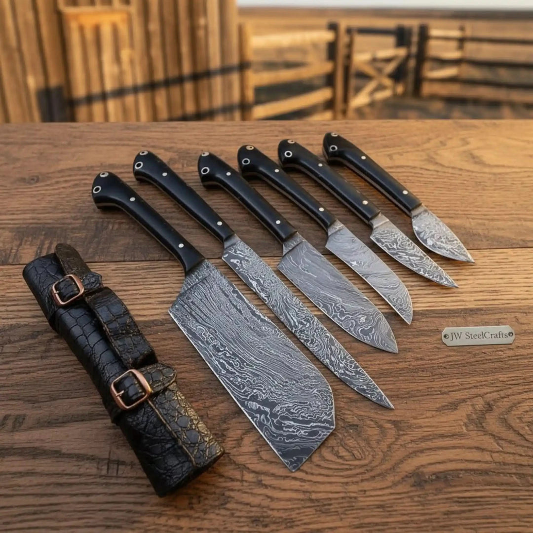 Black handle Damascus knives arranged beside a leather knife organizer on rustic wood.