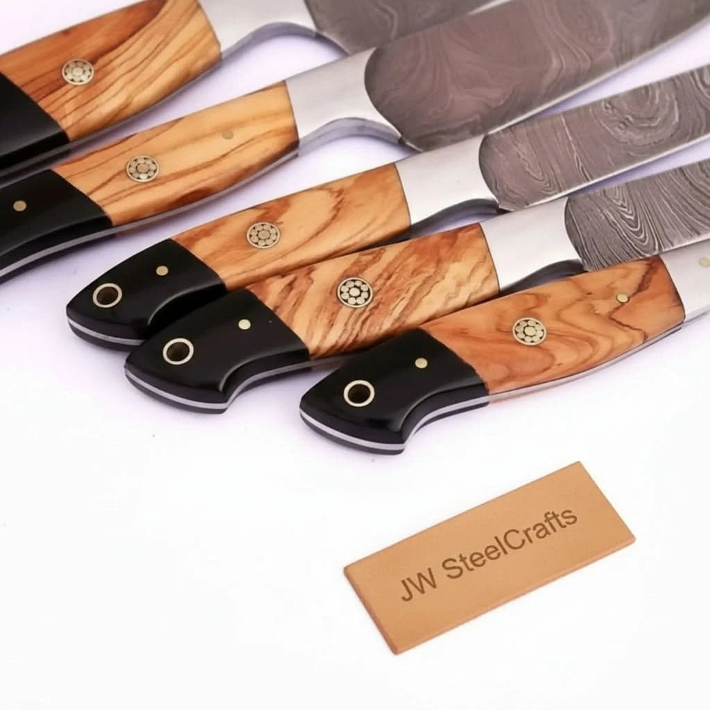 Close-up of Damascus kitchen knives with olive wood and black resin handles