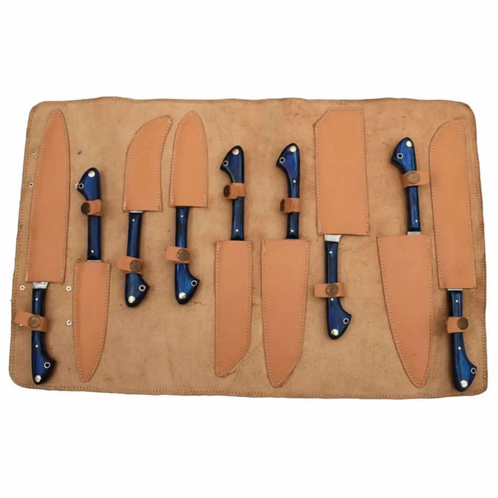 Open tan leather roll case displaying nine Damascus steel kitchen 
knives by JW SteelCrafts, each knife secured in individual leather 
pocket with snap strap and sheath, featuring deep blue full-tang 
Pakkawood handles with brass pins, blades fully sheathed for safe 
storage and transport, laid flat on white background.