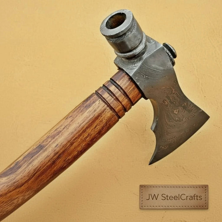     Handmade Damascus steel hatchet with elegant wave-pattern blade and polished wooden grip displayed on a wooden outdoor table.