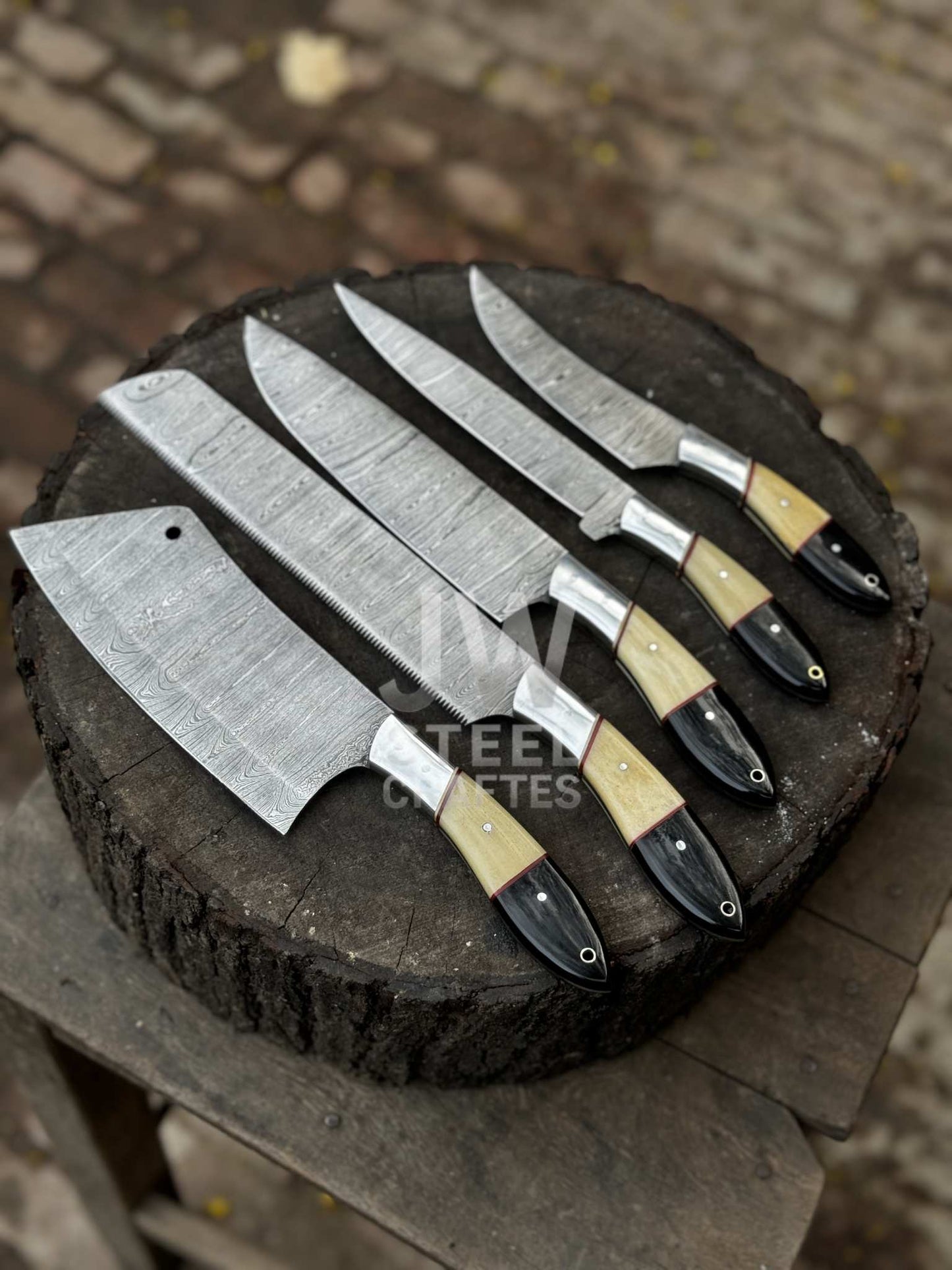 Set of five Damascus knives on a wooden block with a blurred background