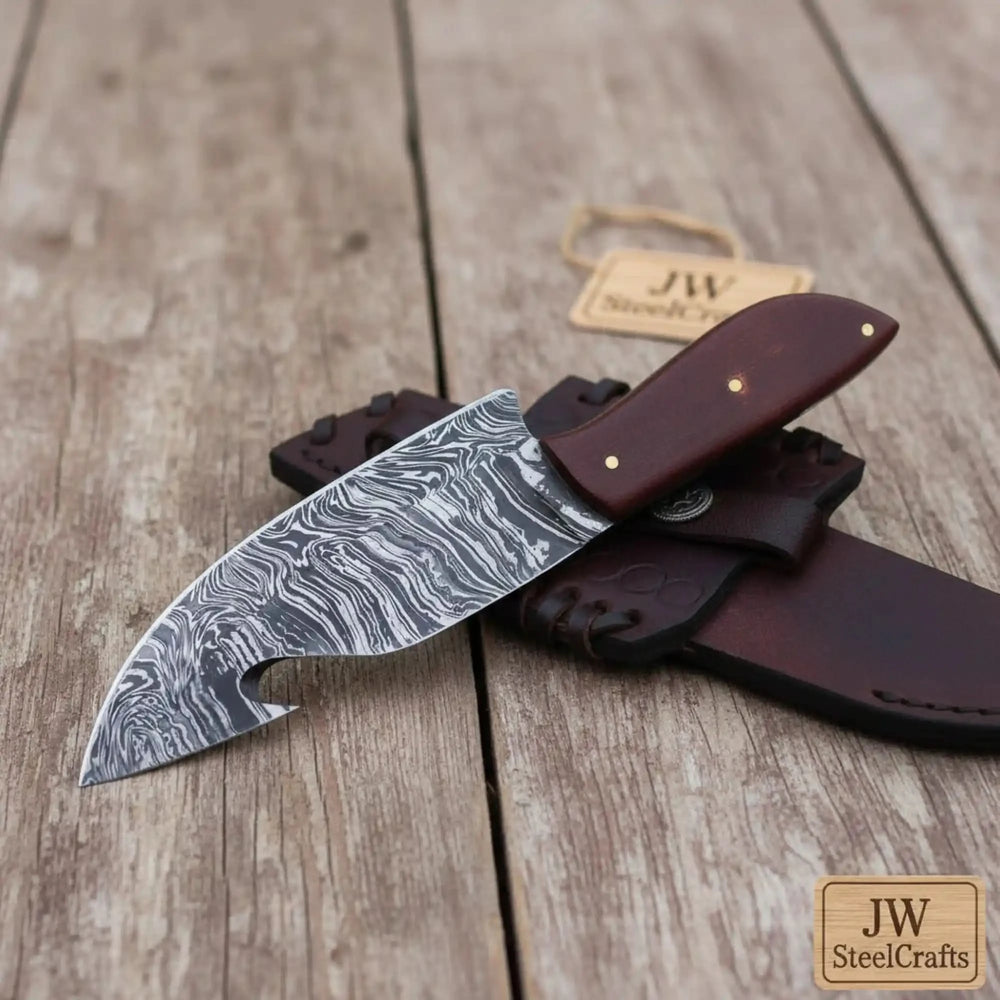 Damascus Steel Gut Hook Knife With Damascus Blade And Brown Leather Sheath On A Wooden Surface.
