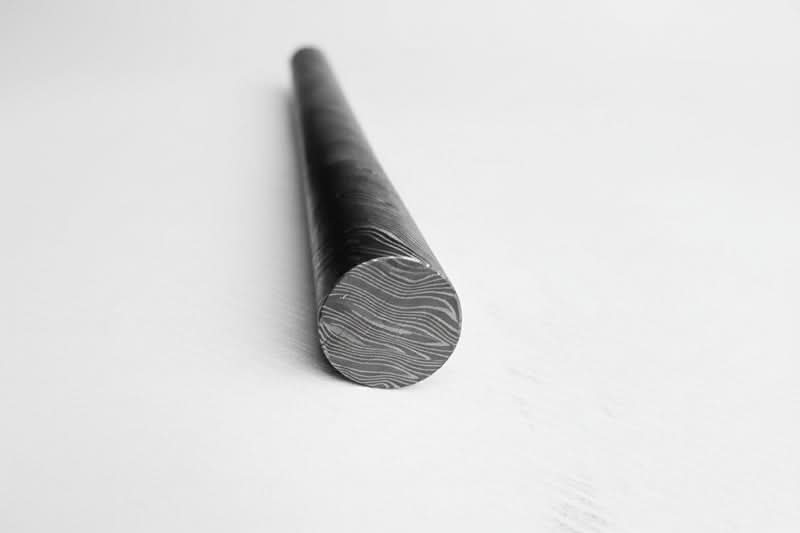 Round Damascus steel bar with visible layered end grain pattern and polished surface for custom knife making materials and metal crafts