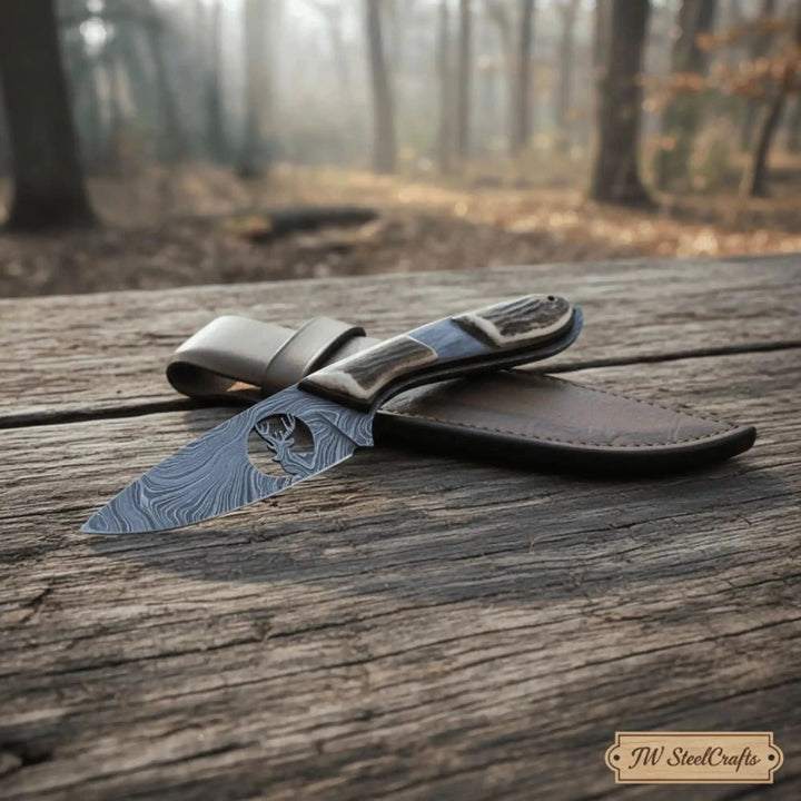 Sharp Damascus skinner with leather holster, deer cutout blade detail, textured handle, and woodland product photography.