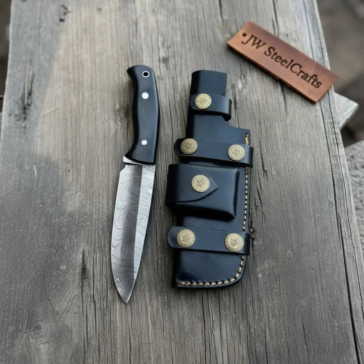 Multi-strap black leather sheath with brass snaps paired with a fixed blade knife 
