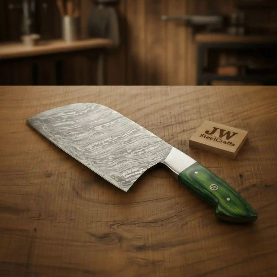 Woodgrain display showing a Damascus cleaver knife with silver collar and green grip