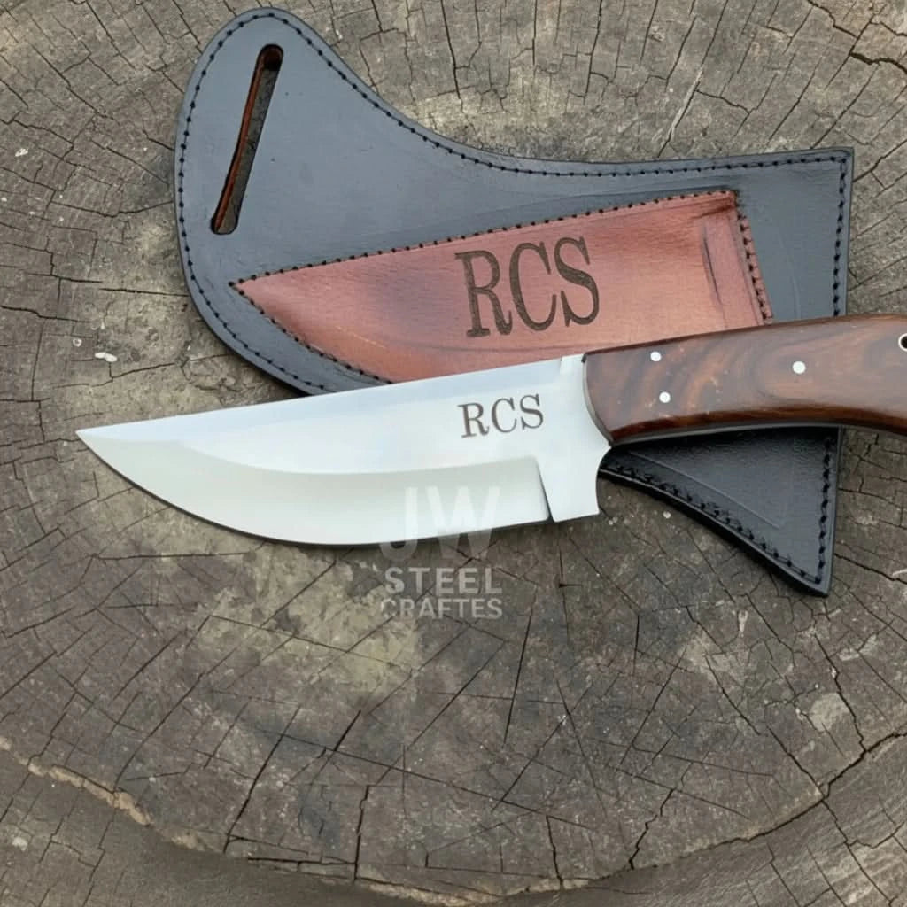 Personalized wood handle knife with RCS blade engraving displayed on a weathered tree stump beside a fitted leather sheath.