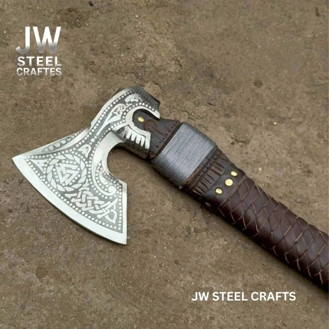 Close-up of a handcrafted Norse battle axe featuring decorative silver engravings and braided leather handle wrapping.