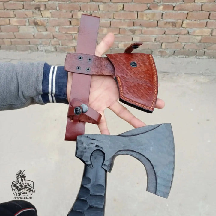 Falconforge-themed Norse battle weapons featuring textured forged steel hatchets crossed on stone outdoors.