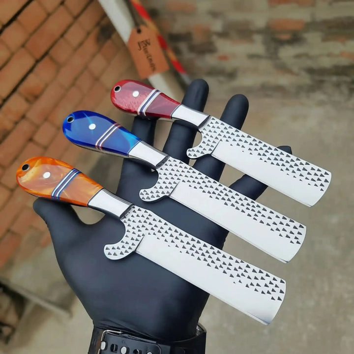 Three-toned in orange, blue, and red resin handles, this razor set with dimpled blades is displayed in a black-gloved hand