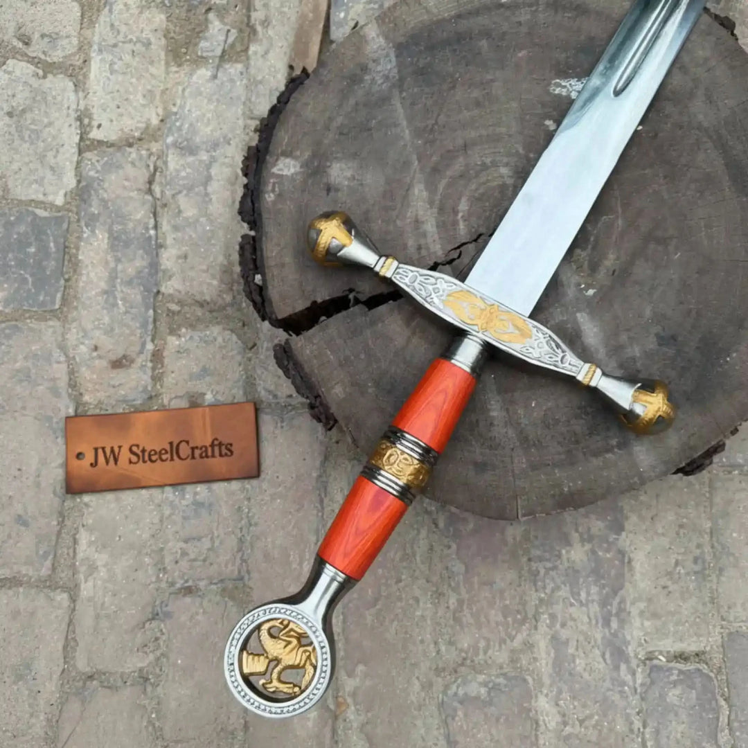 Collectible medieval-style sword with detailed gold engravings and red wooden grip displayed on a rustic tree stump