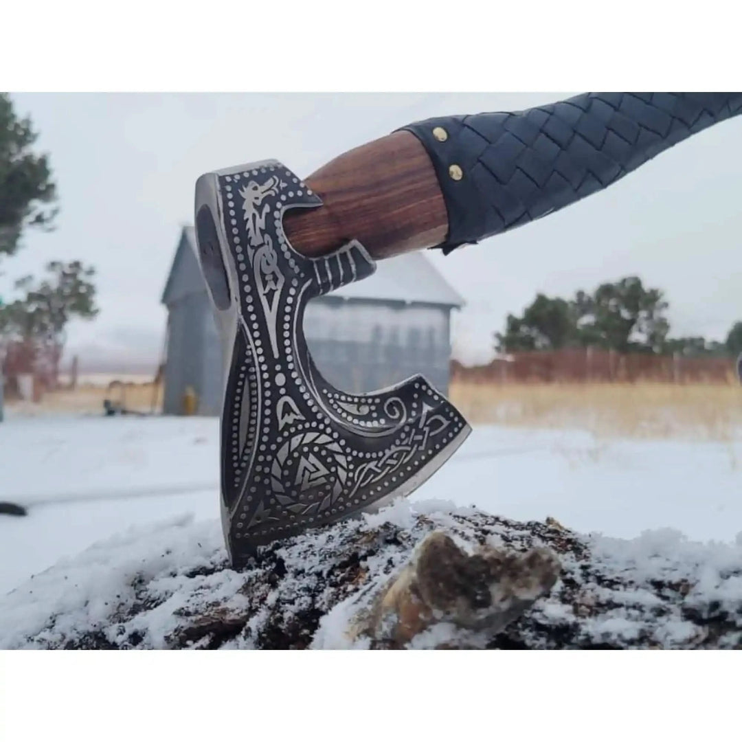 Premium Nordic axe close-up showing detailed blade engravings and textured black handle wrapping.