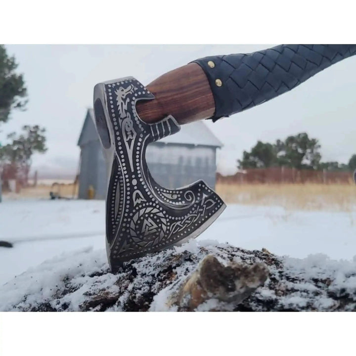 Premium Nordic axe close-up showing detailed blade engravings and textured black handle wrapping.