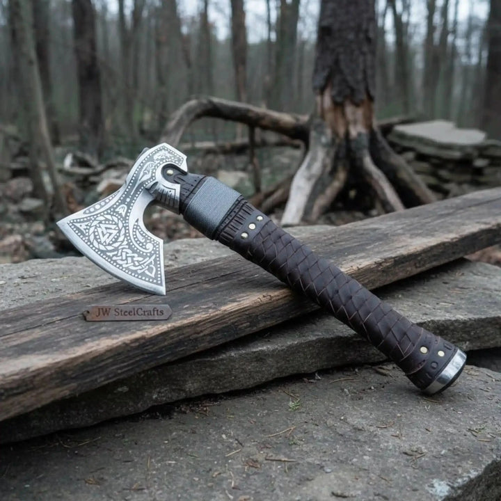 Handcrafted Nordic war hatchet featuring engraved blade artwork and rustic braided leather craftsmanship.