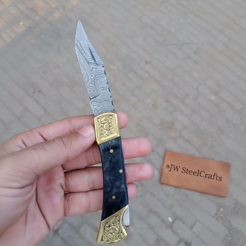     Silvercreek Damascus slipjoint knife with brass detail work and layered steel blade held in hand