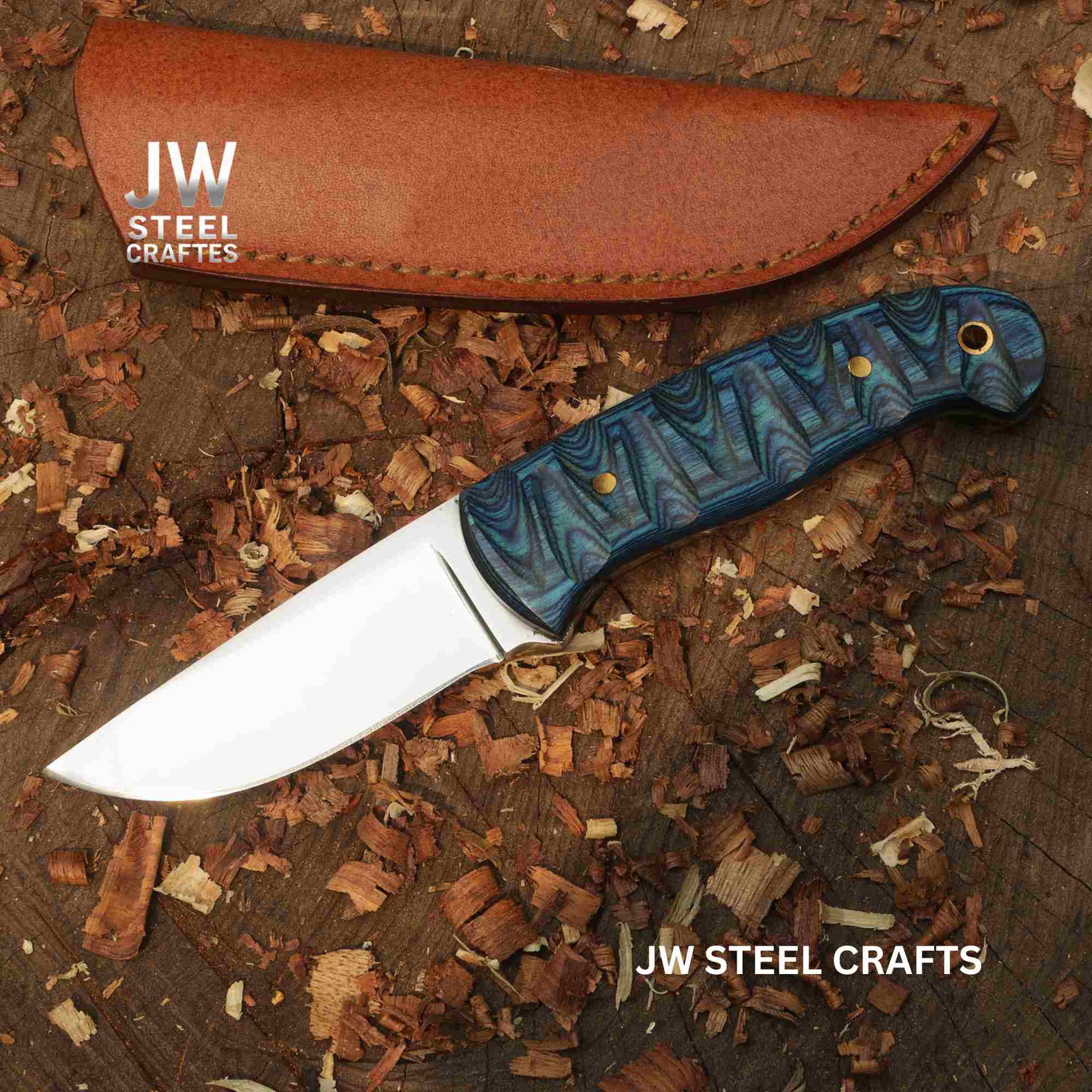 Knife with blue handle and leather sheath on a wooden surface, branded 'JW Steel Crafts'.