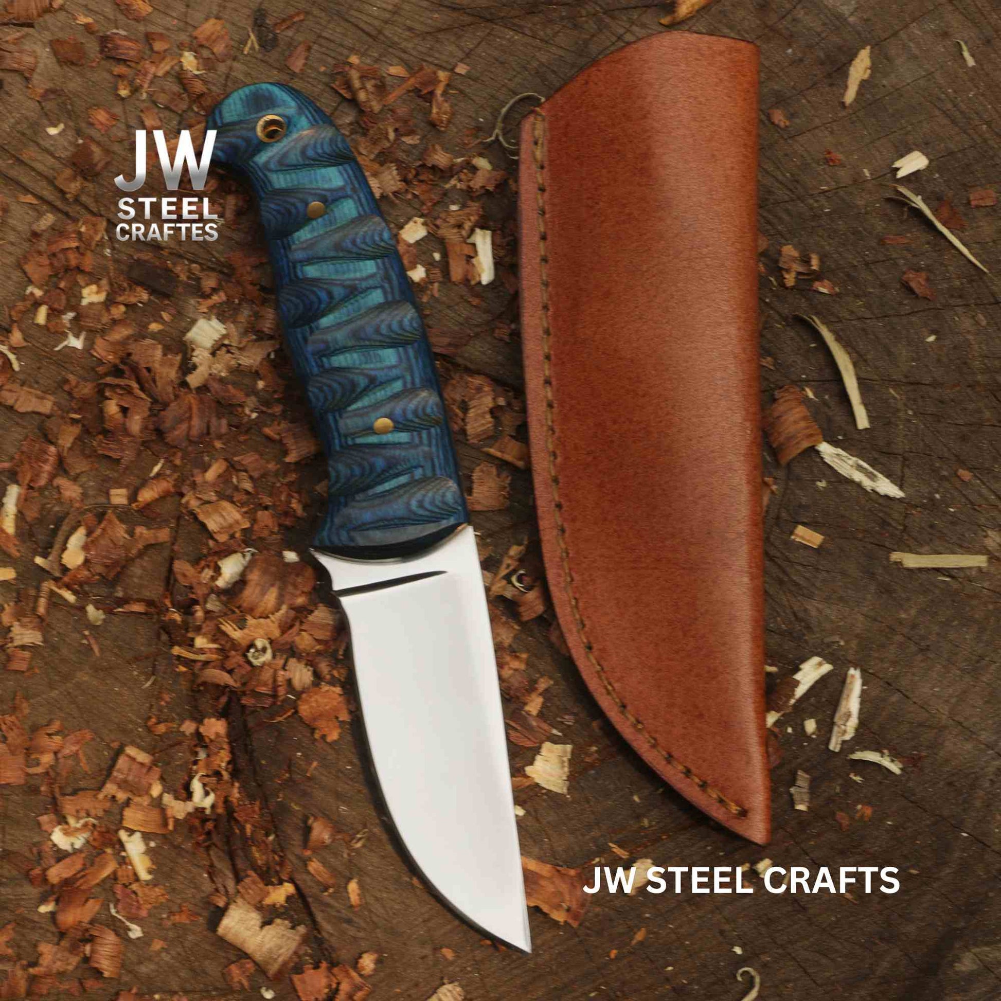 Forked-tongue knife with blue handle and brown sheath on a wooden surface, branded 'JW Steel Crafts'.