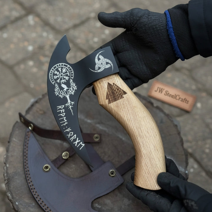 Close-up of a handcrafted bushcraft hatchet featuring a black steel blade with engraved symbols and a smooth wooden grip.