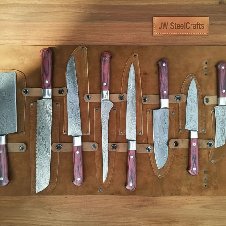 Multiple handcrafted Damascus steel kitchen knives with purple wood handles secured inside brown leather chef knife roll organizer.
