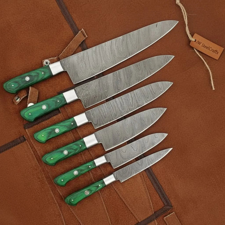Luxury culinary blades showcasing decorative Damascus wave textures and ergonomic emerald wood style grip craftsmanship.