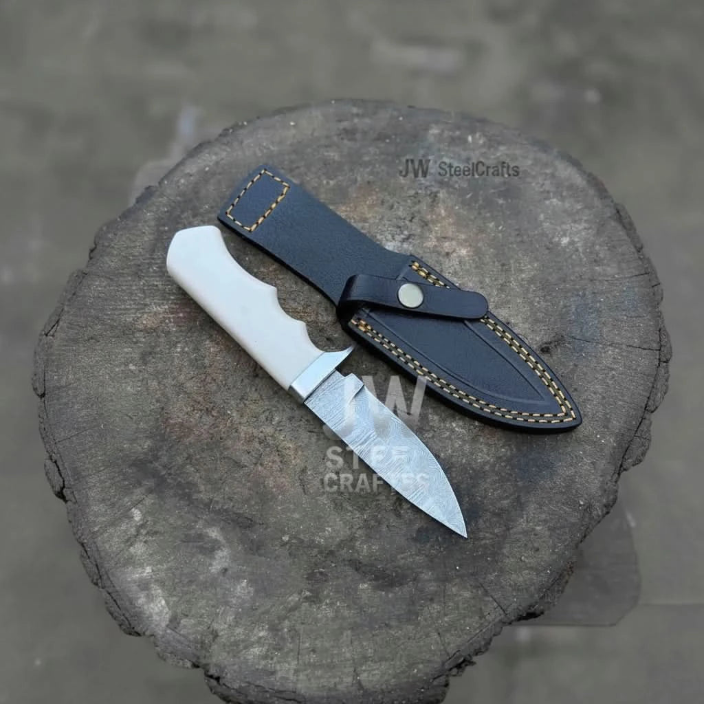 Black leather sheath with yellow stitching shown next to a small fixed blade knife with a white handle