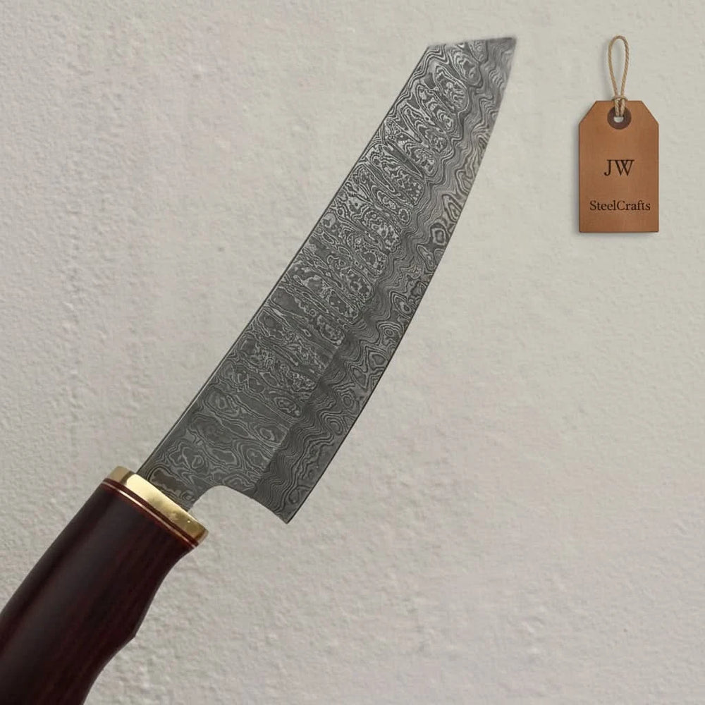 Angled tip Damascus chef blade showing detailed layered steel pattern and brass bolster