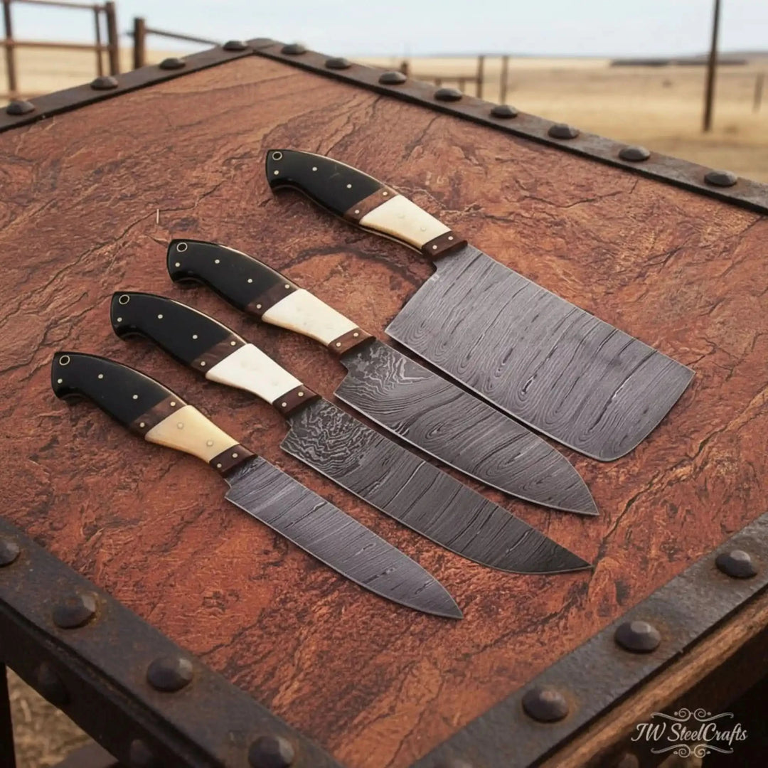 Four handcrafted Damascus steel kitchen knives with dark wood and ivory accent handles displayed on rustic textured tabletop outdoors.