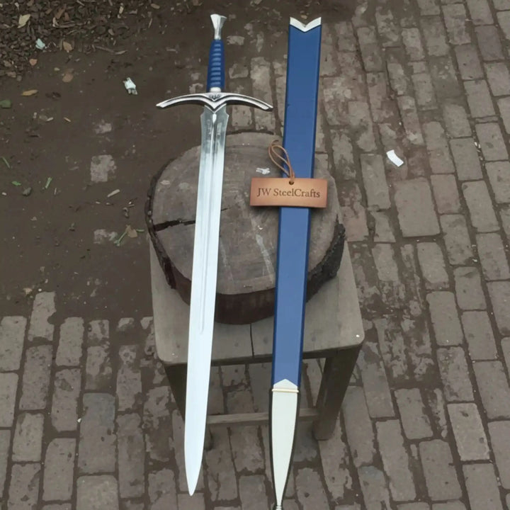 A striking medieval longsword with a polished blade, ornate silver winged crossguard, and blue ribbed handle, paired with a matching blue leather scabbard on a cobblestone surface.