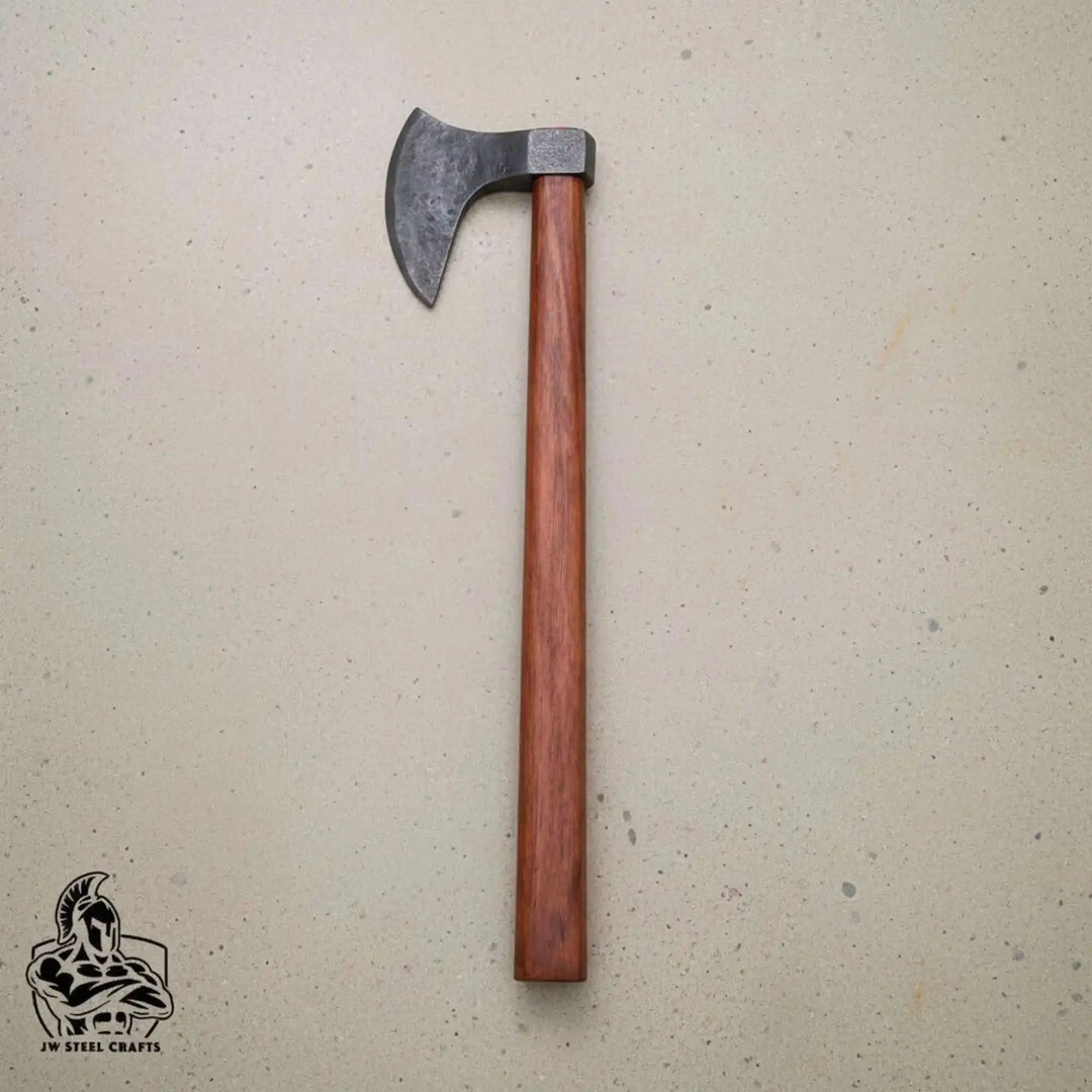 Lionclaw-themed Nordic war hatchet featuring polished Damascus blade and handcrafted wooden grip outdoors.