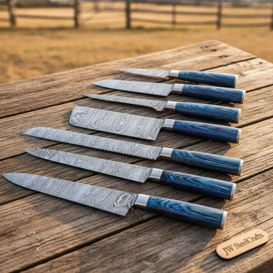 Kitchen knives with Damascus pattern blades and handcrafted blue ergonomic handles.