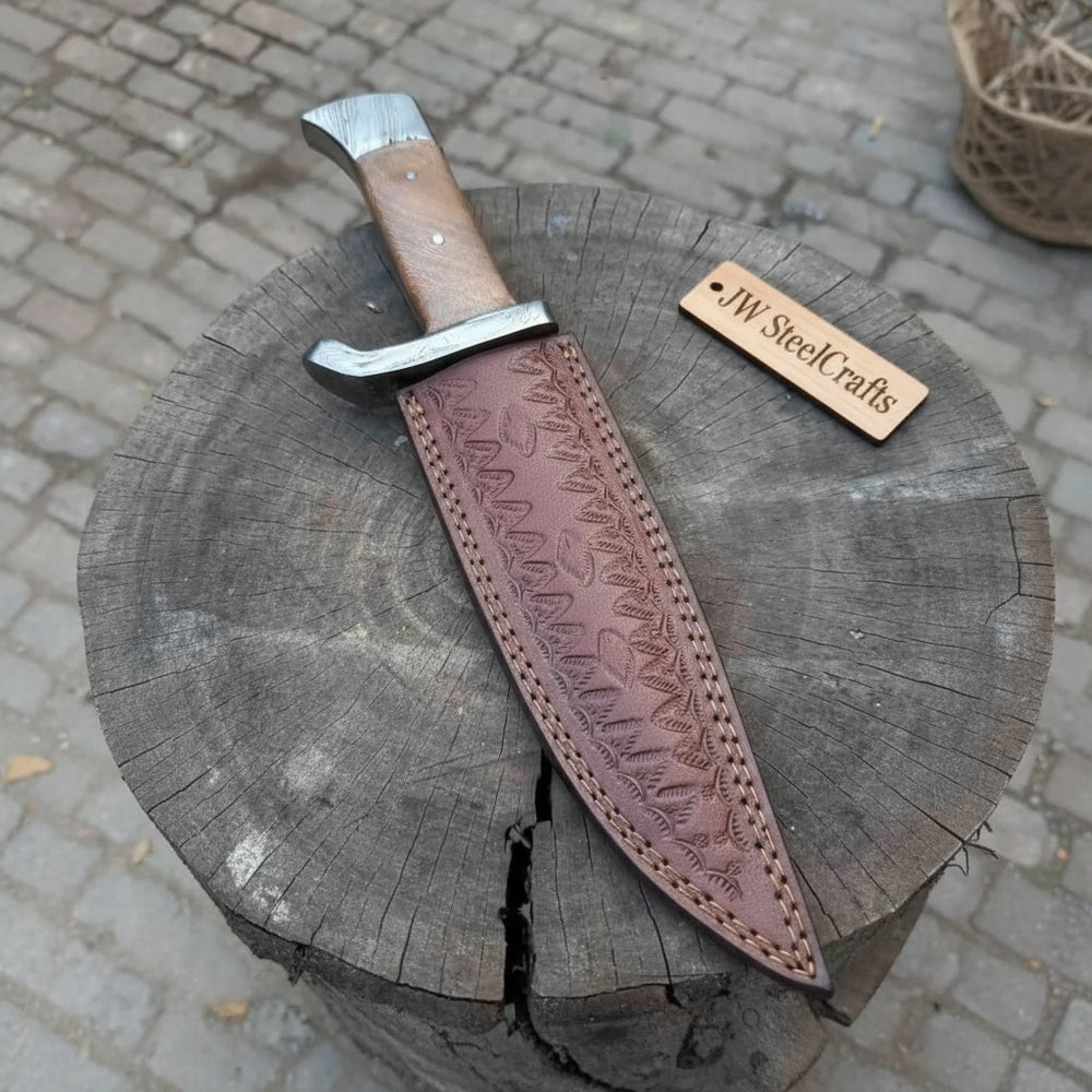 Damascus hunting knife with guard and sheath, long curved blade, wooden handle, and brown tooled leather case.