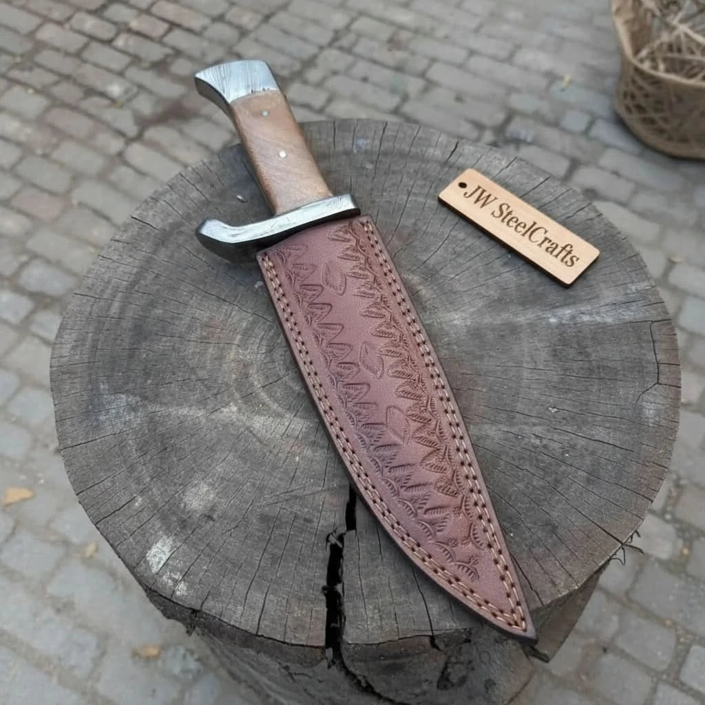 Damascus hunting knife with guard and sheath, long curved blade, wooden handle, and brown tooled leather case.