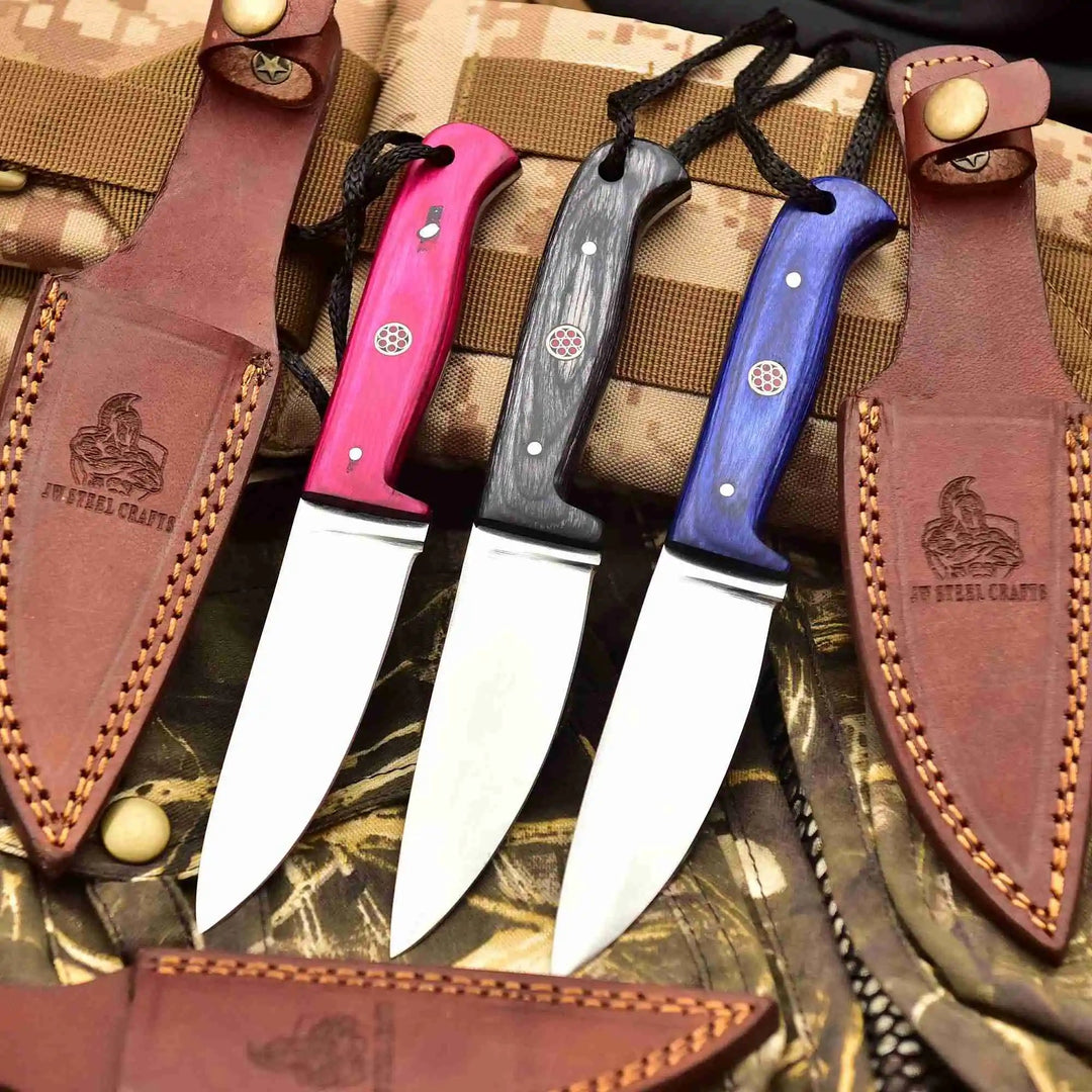 Camping knife set with polished steel blades, colorful wood handles, lanyard holes, and protective brown leather sheaths.