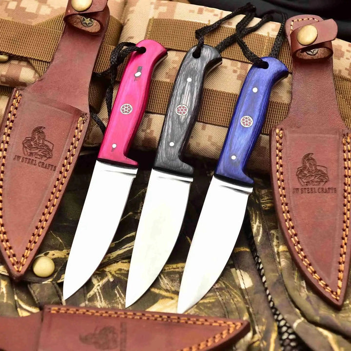 Camping knife set with polished steel blades, colorful wood handles, lanyard holes, and protective brown leather sheaths.