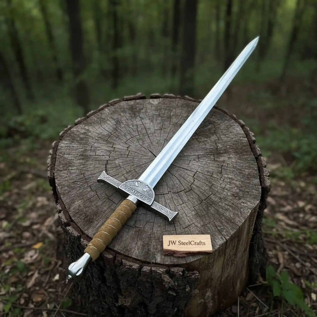 Overhead view of a handforged longsword with a straight silver blade and natural wood grip, resting diagonally across a cobblestone street surface.