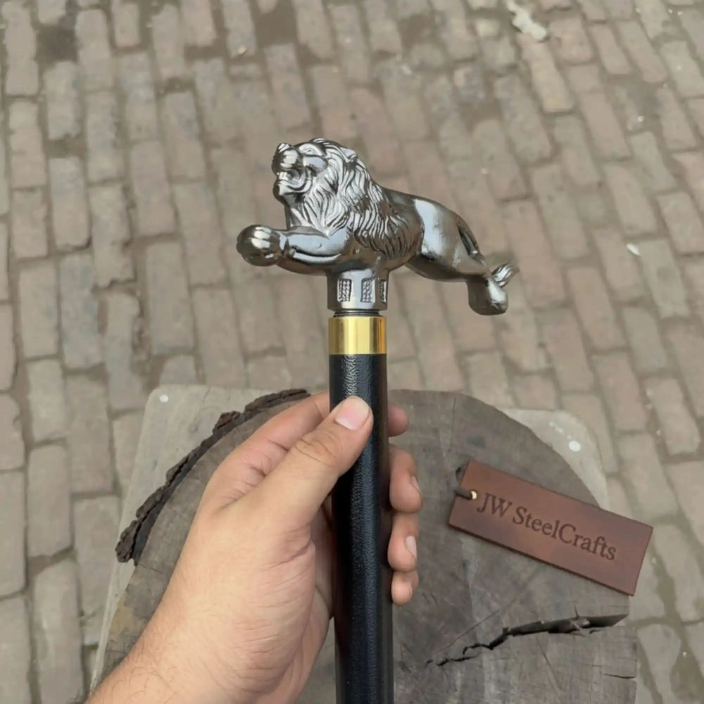 Silver lion sculpture atop a black cane shaft, connected by a polished brass collar, a handcrafted product by JW SteelCrafts.