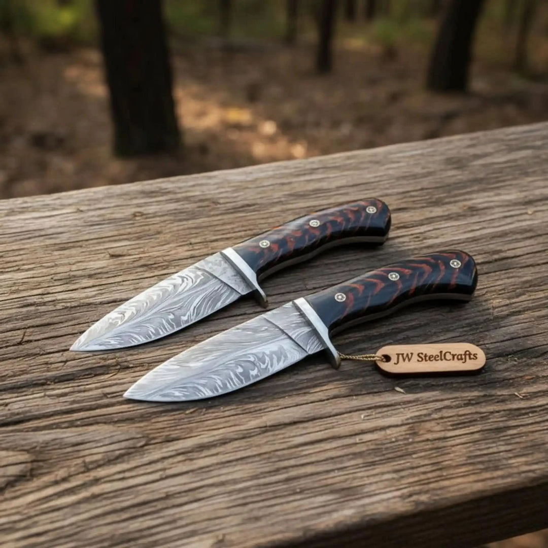 Two fixed blade Damascus knives in rustic display with matching dark handles, silver guards