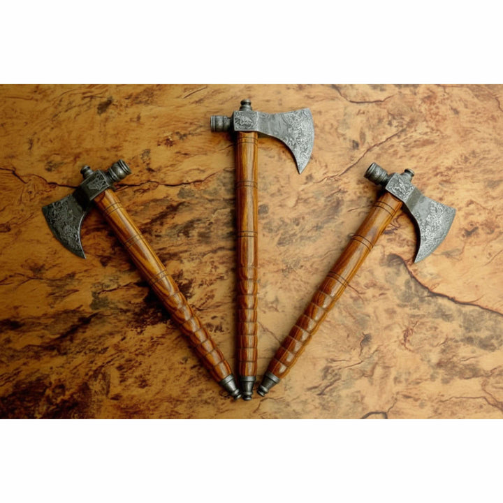     Handcrafted Norse battle hatchets with decorative steel heads and smooth carved wood handles arranged on textured background.