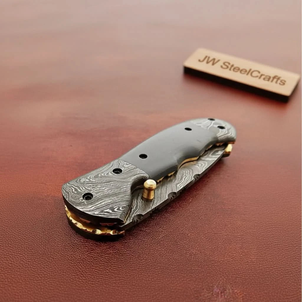    Refined Damascus folding knife showcasing drop style blade and polished handcrafted handle details