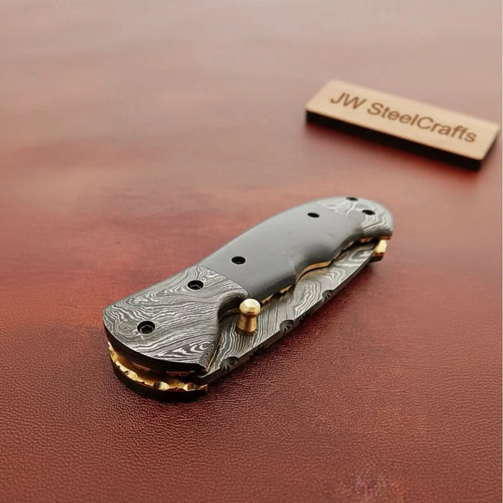     Refined Damascus folding knife showcasing drop style blade and polished handcrafted handle details