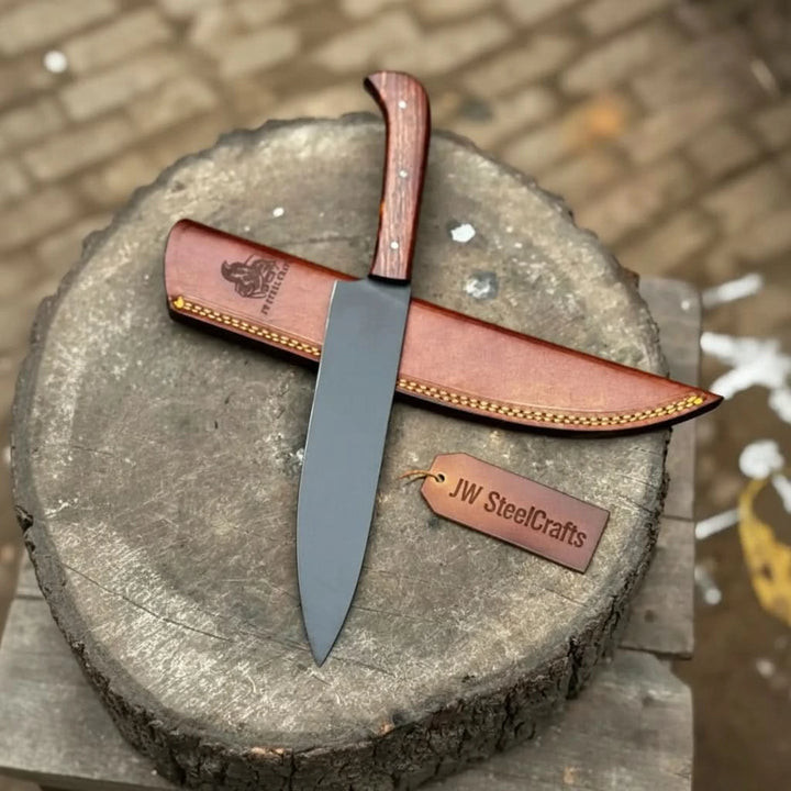 Rustic chef knife displayed vertically on a cut wood stump with leather blade cover