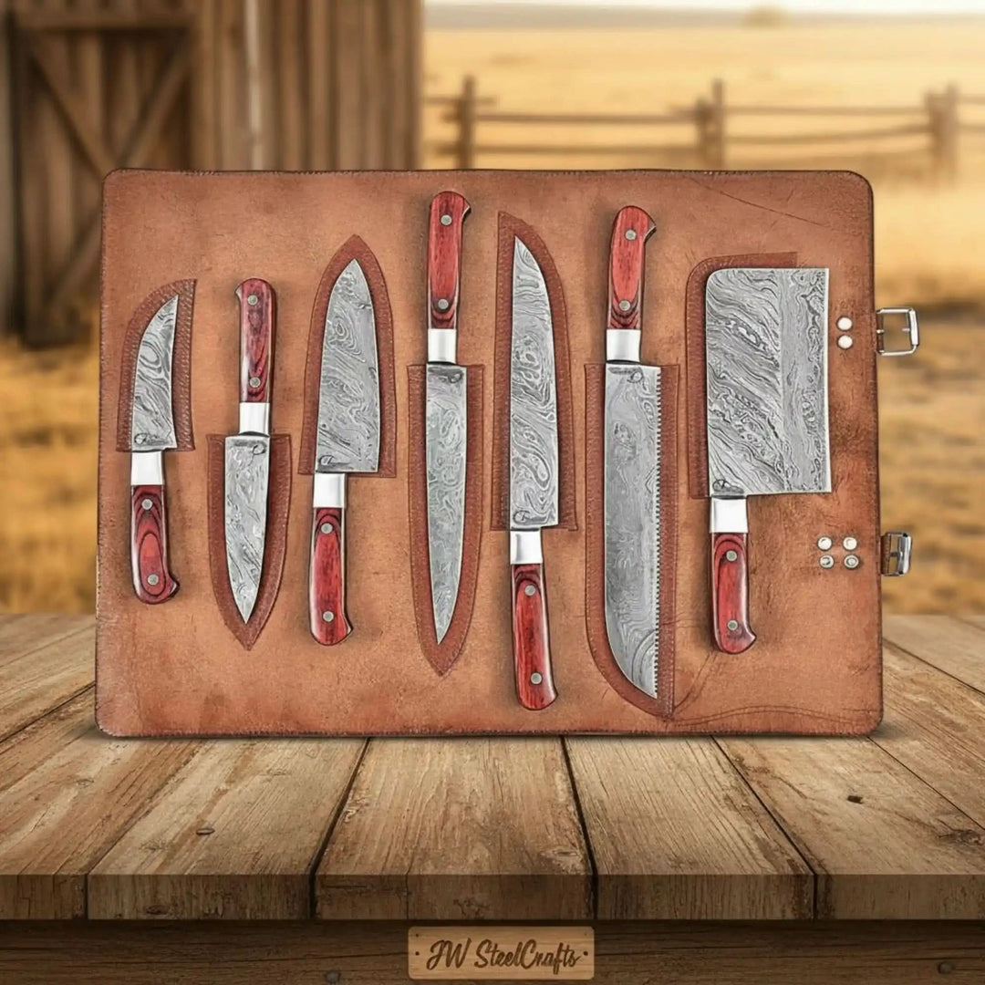 Damascus knife set with patterned steel blades and red wood handles stored in leather knife roll.